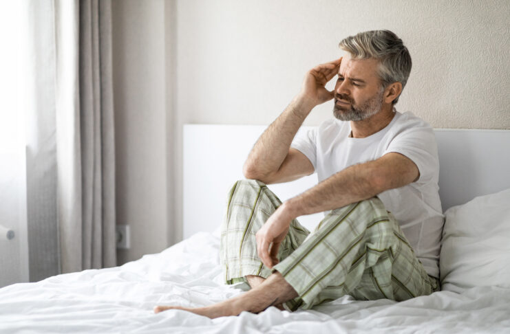 Sad middle aged man sitting in bed, touching his head Beat Sunday Night Work Anxiety