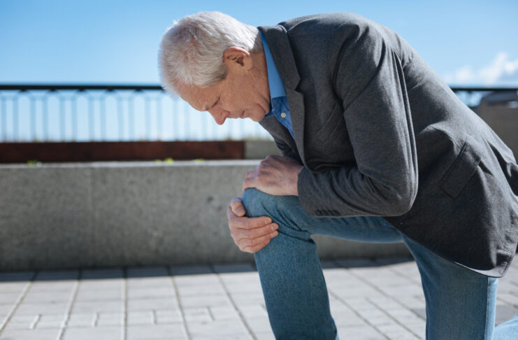 Concentrated pensioner suffering from knee ache in the park Why Your Knees Creak After 35