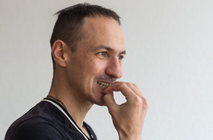 Frightened man feeling scared and biting his nails on a light background. Chewing Patterns Reshape Your Jawline